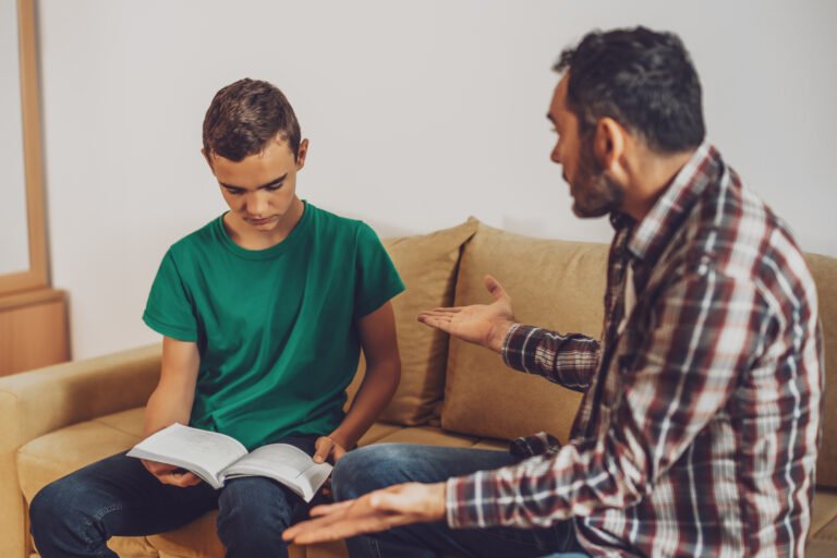 Teen with a book speaking with an adult for Ajax ADHD parent guide