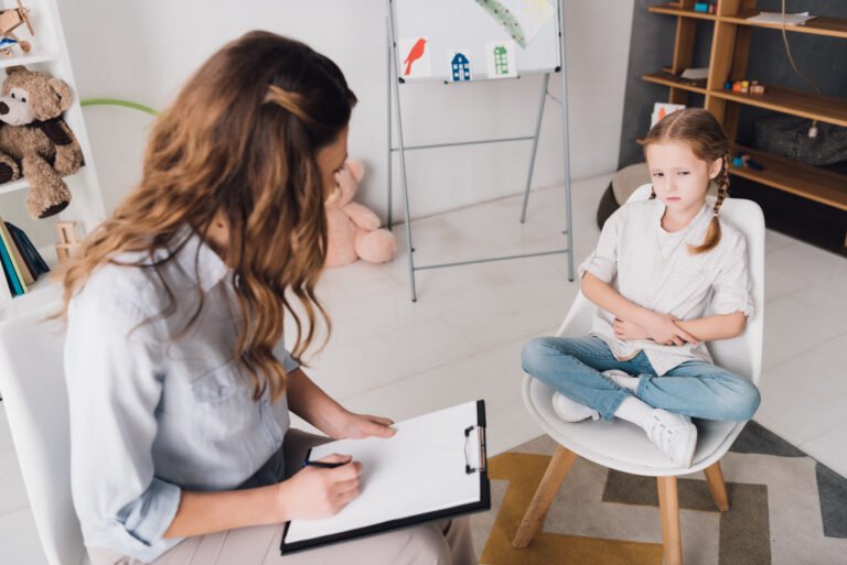 Girl seated across from a woman holding a clipboard.